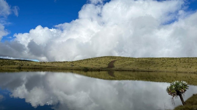 Two local cooks smiling while preparing a meal in a mountain hut kitchen.