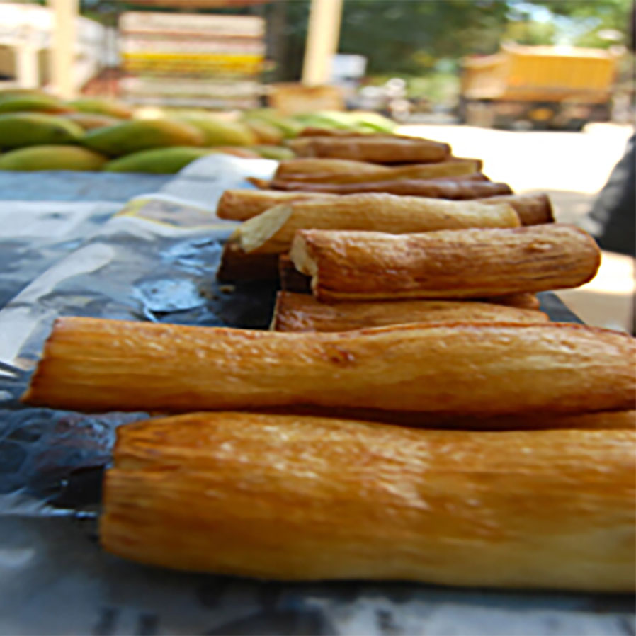 Roasted cassava pieces arranged in a row on a street vendor’s counter.