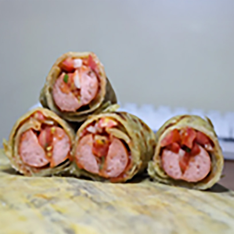 Close-up of sliced Kenyan smocha wraps filled with sausage and kachumbari, stacked on a wooden surface.