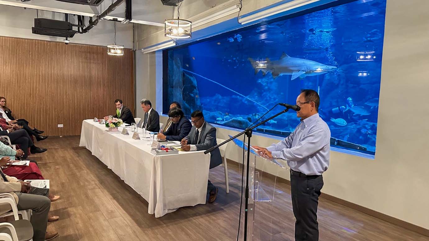 Panel discussion during the marine station opening event at the Odysseo Oceanarium, with speakers seated in front of a large aquarium.