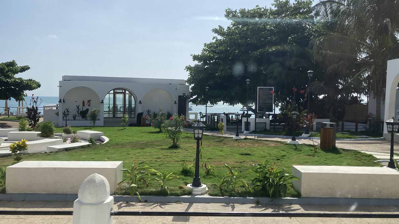 Landscaped garden and white historic building facing the ocean along Stone Town’s seafront.