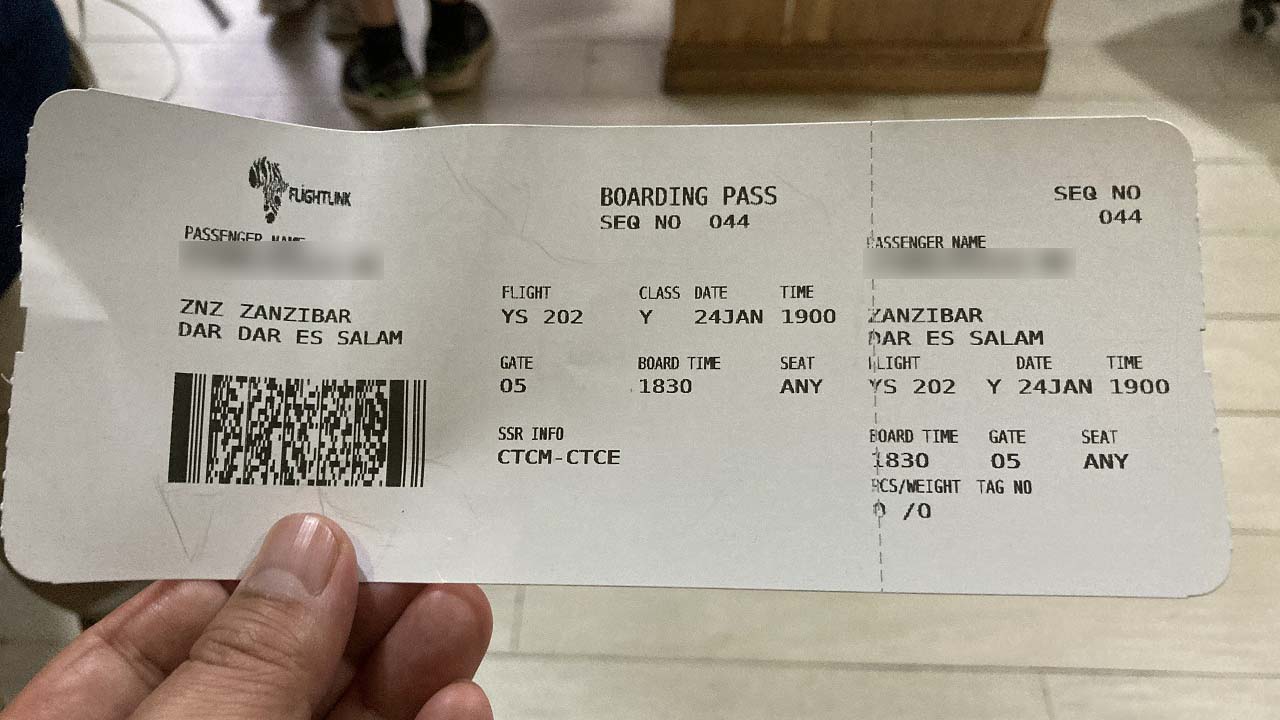 Boarding pass for a Flightlink flight between Zanzibar and Dar es Salaam held in hand.
