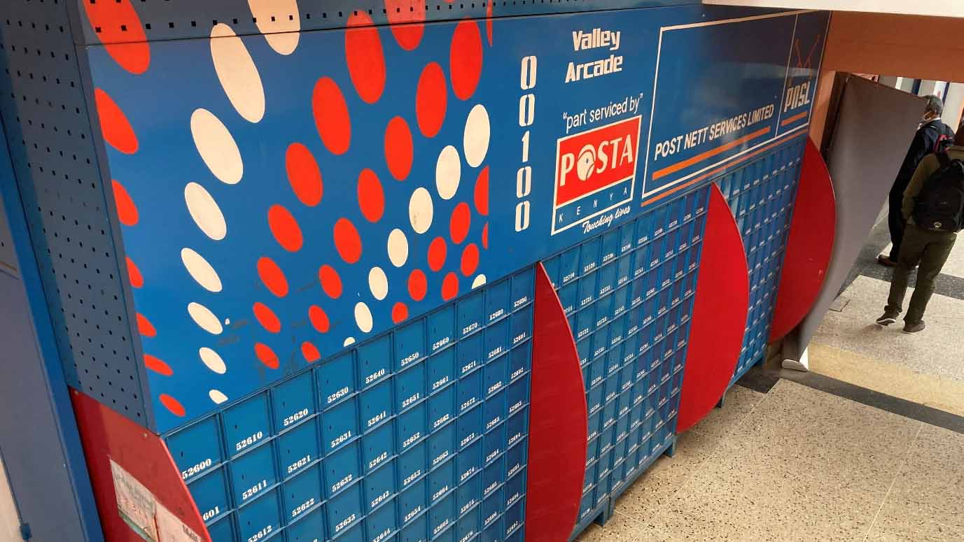 Local courier on a motorcycle delivering a parcel in a residential area, representing last-mile delivery in Kenya where mobile contact and flexible routing are essential.