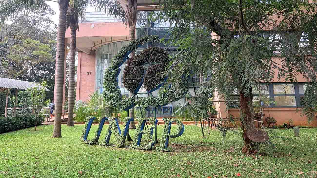 UNEP logo-shaped garden display surrounded by trees and greenery on the grounds of the United Nations Office in Nairobi.