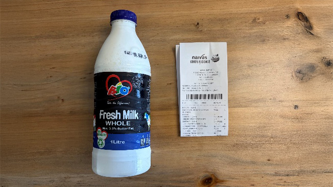 A one-litre bottle of fresh whole milk beside a supermarket receipt in Nairobi