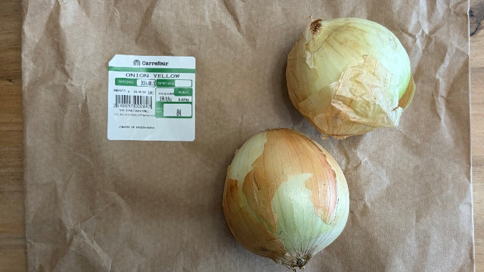 Two yellow onions with a supermarket price label in Nairobi.