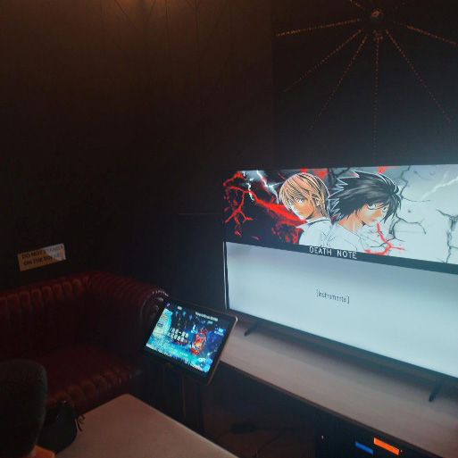 Private karaoke room with a screen displaying anime content