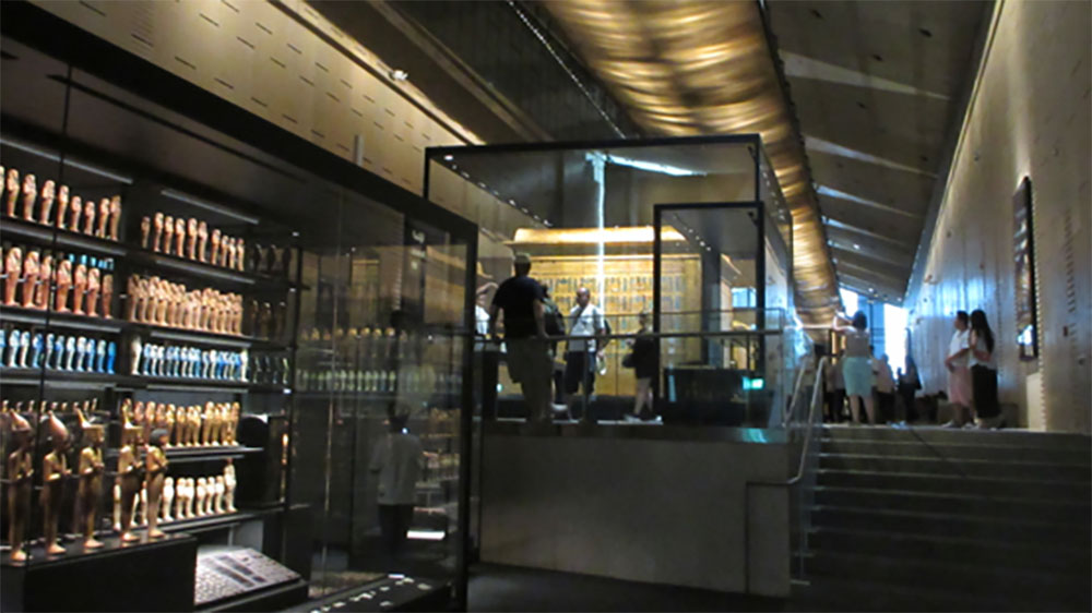 Ancient Egyptian artifacts and figurines displayed in illuminated glass cases inside the Grand Egyptian Museum, offering visitors a glimpse into Egypt’s rich archaeological heritage.